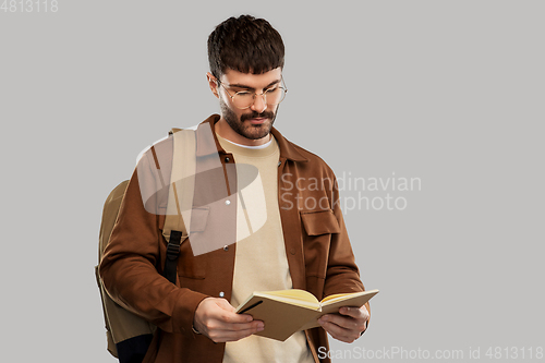 Image of young man with backpack reading diary