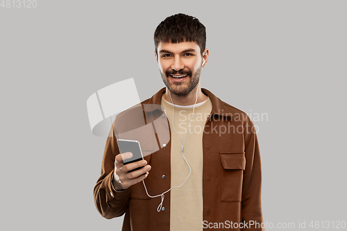 Image of smiling young man with earphones and smartphone