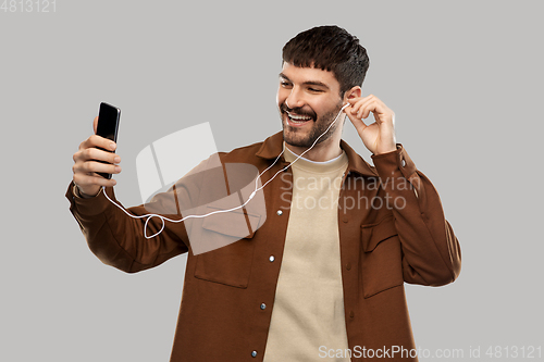 Image of smiling young man with earphones and smartphone