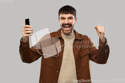 Image of smiling young man with earphones and smartphone