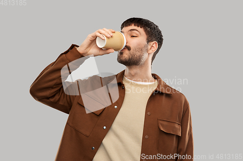 Image of happy young man drinking coffee from takeaway cup