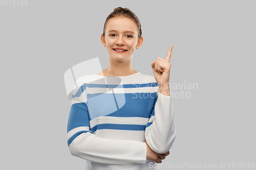 Image of happy teenage girl in pullover pointing finger up