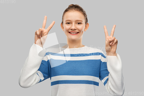 Image of smiling teenage girl showing peace hand sign