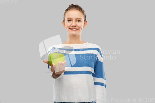 Image of smiling teenage girl in pullover with green apple