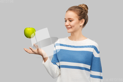 Image of smiling teenage girl in pullover with green apple