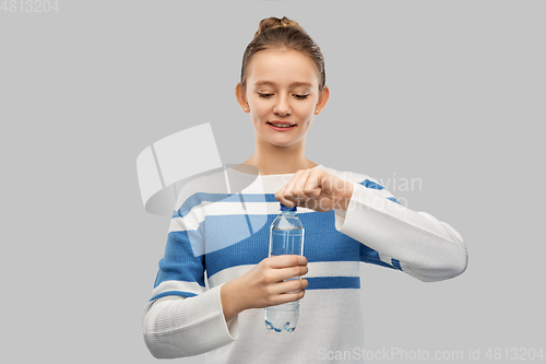 Image of smiling teenage girl opening bottle of water