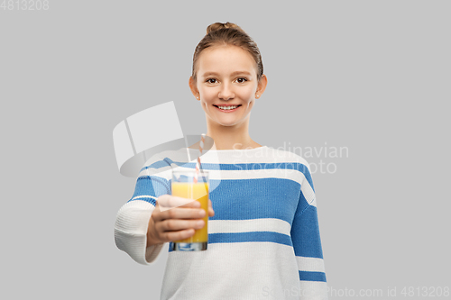 Image of smiling teenage girl holding glass of orange juice