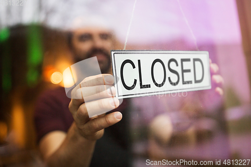 Image of owner puts closed sign at bar or restaurant window