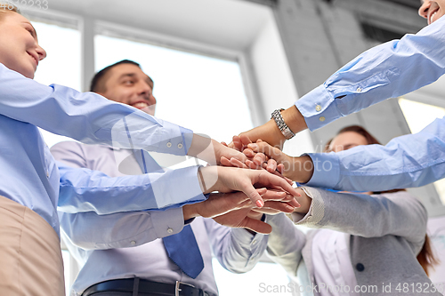 Image of close up of business team stacking hands at office