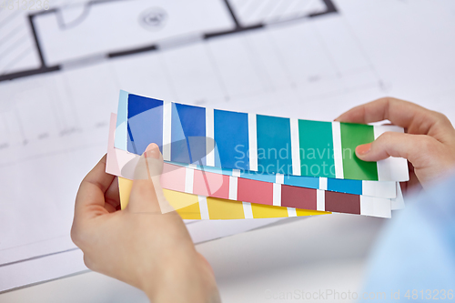 Image of designer's hands with color palettes and blueprint