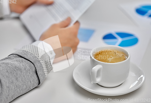 Image of hands of businesswoman and cup of coffee at office