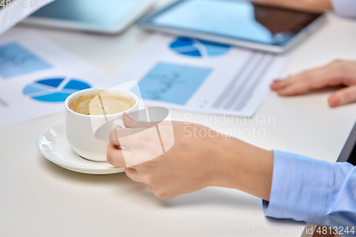 Image of hand of businesswoman drinking coffee at office