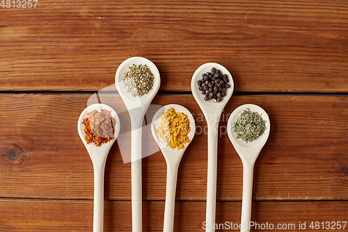 Image of spoons with different spices on wooden table