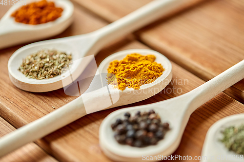 Image of spoons with different spices on wooden table