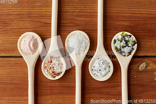 Image of spoons with salt and spices on wooden table