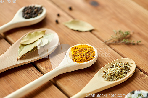 Image of spoons with different spices on wooden table