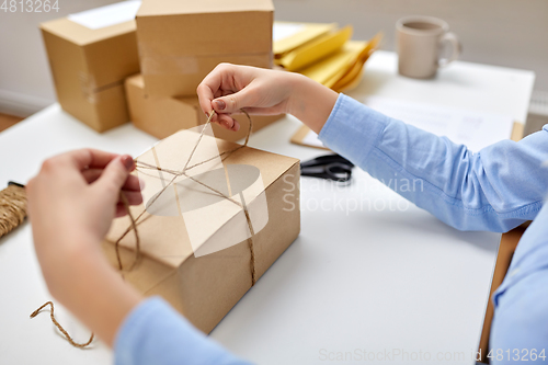 Image of woman packing parcel and tying rope at post office