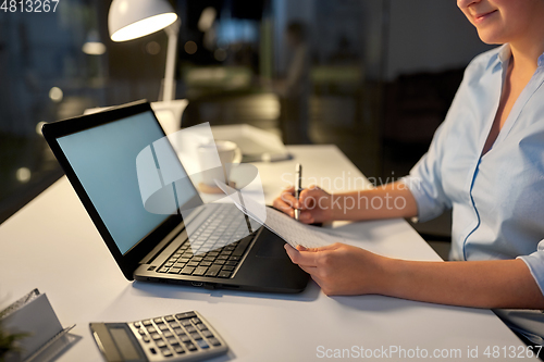 Image of businesswoman with papers working at night office