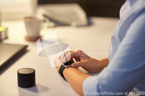 Image of woman with smart watch and speaker at night office
