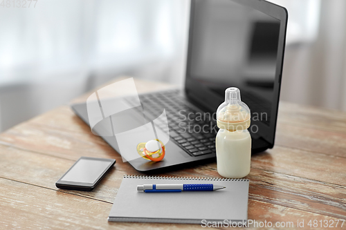 Image of baby milk formula, laptop and notebook on table