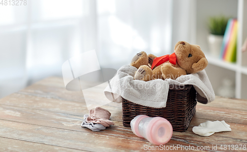 Image of teddy bear toy in basket with baby things on table