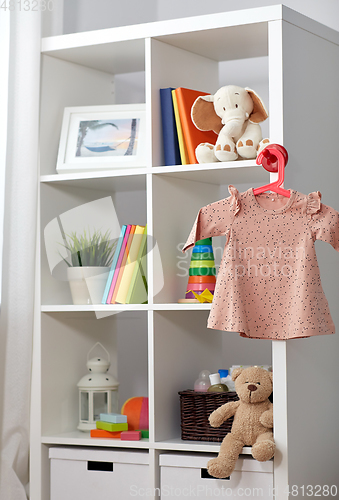 Image of kid's room interior with bookcase and baby dress