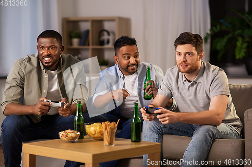 Image of happy friends playing video games at home at night
