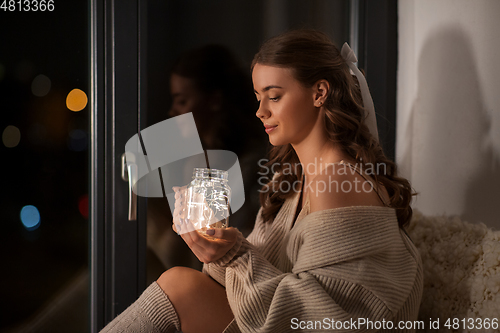 Image of woman with garland lights in glass mug at home