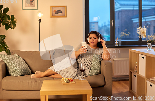 Image of woman in headphones listens to music on smartphone