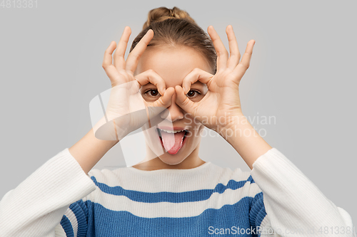 Image of funny teenage girl looking through finger glasses