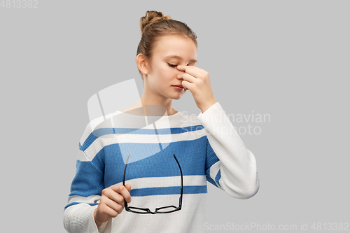 Image of teenage girl with glasses rubbing nose bridge