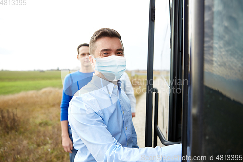 Image of male passenger in medical mask boarding travel bus