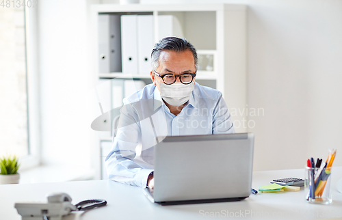 Image of businessman in medical mask with laptop at office