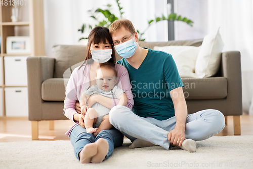 Image of family with baby in medical masks at home