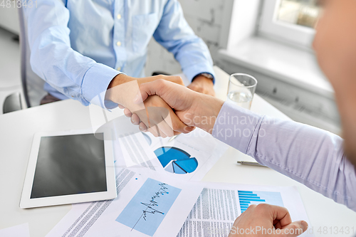 Image of close up of businessmen making handshake at office