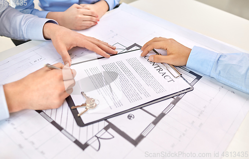 Image of hands signing property purchase contract at office