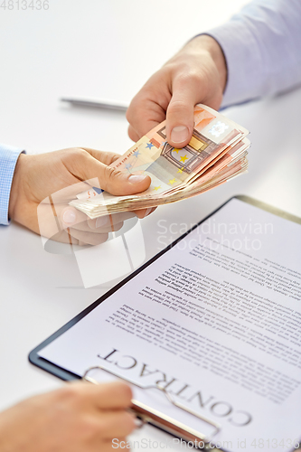 Image of close up of hands with euro money and contract