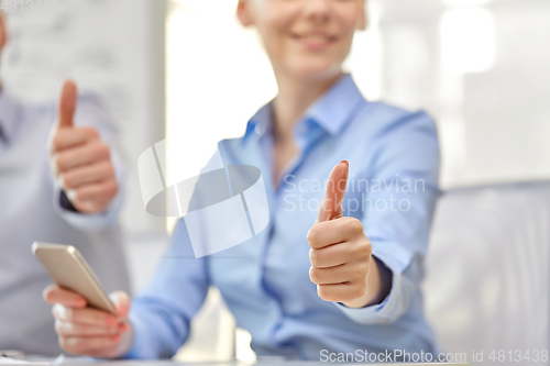 Image of portrait of smiling young woman showing thumbs up