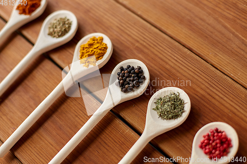 Image of spoons with different spices on wooden table