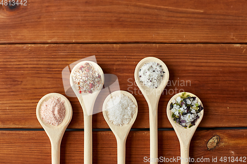 Image of spoons with salt and spices on wooden table