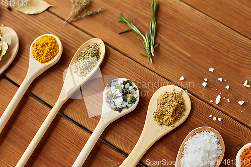 Image of spoons with spices and salt on wooden table