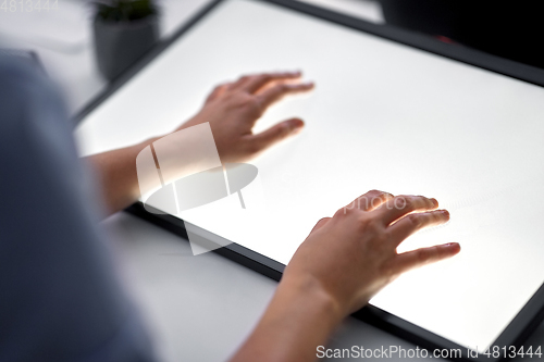 Image of hands on led light tablet at night office