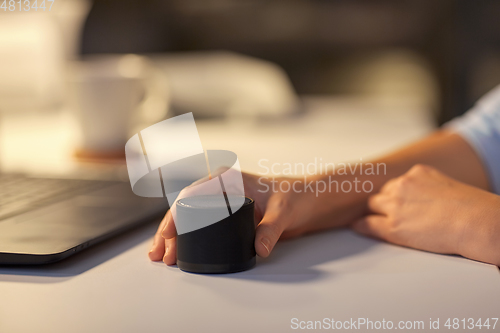 Image of close up of hand with smart speaker at office