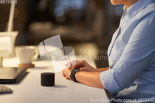 Image of woman with smart watch and speaker at night office