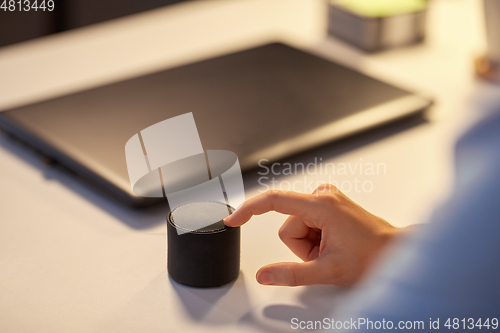 Image of close up of hand with smart speaker at office