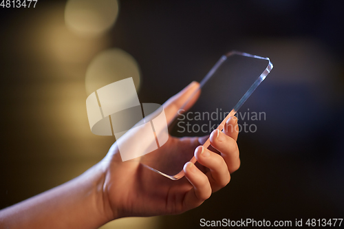 Image of close up of hand with transparent smartphone