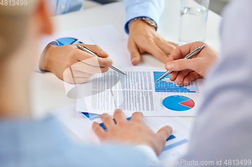 Image of business team hands with pens and charts at office