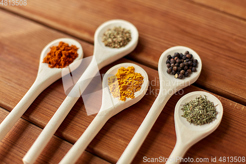 Image of spoons with different spices on wooden table