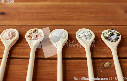 Image of spoons with salt and spices on wooden table