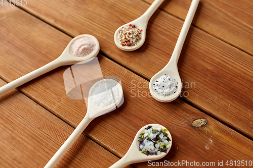 Image of spoons with salt and spices on wooden table